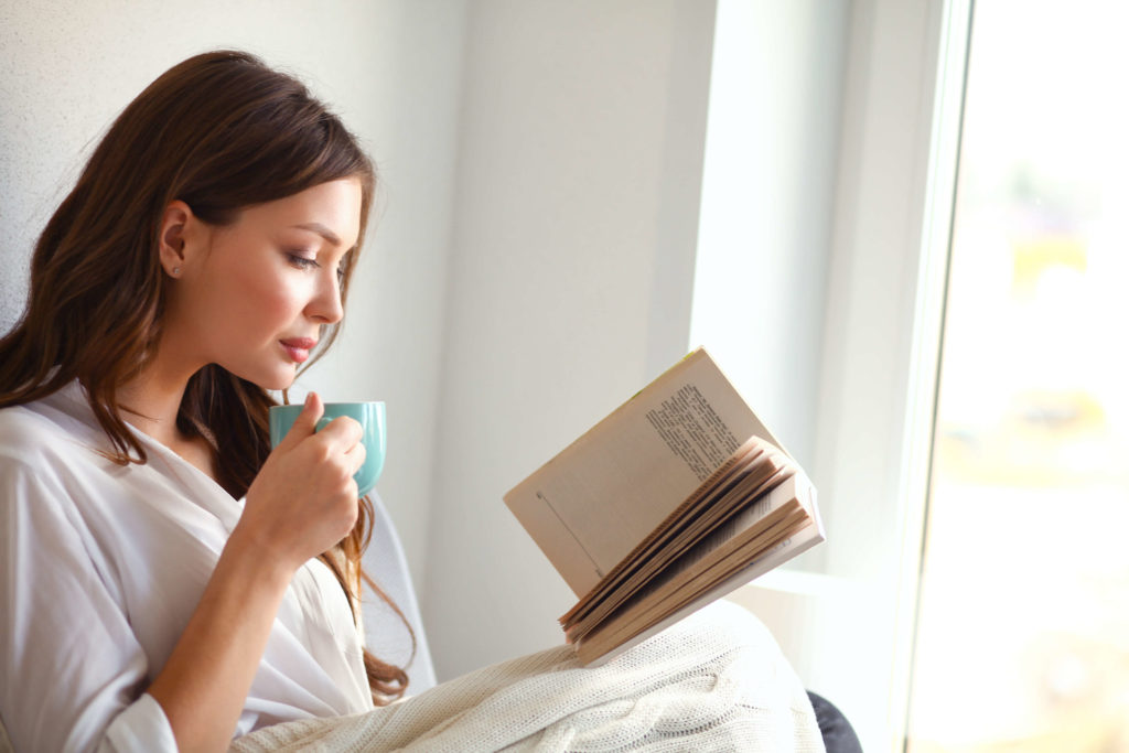 woman drinking coffee reading a book 