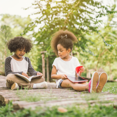 Two African American Children sitting on a bridge with books
