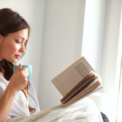 woman drinking coffee reading a book